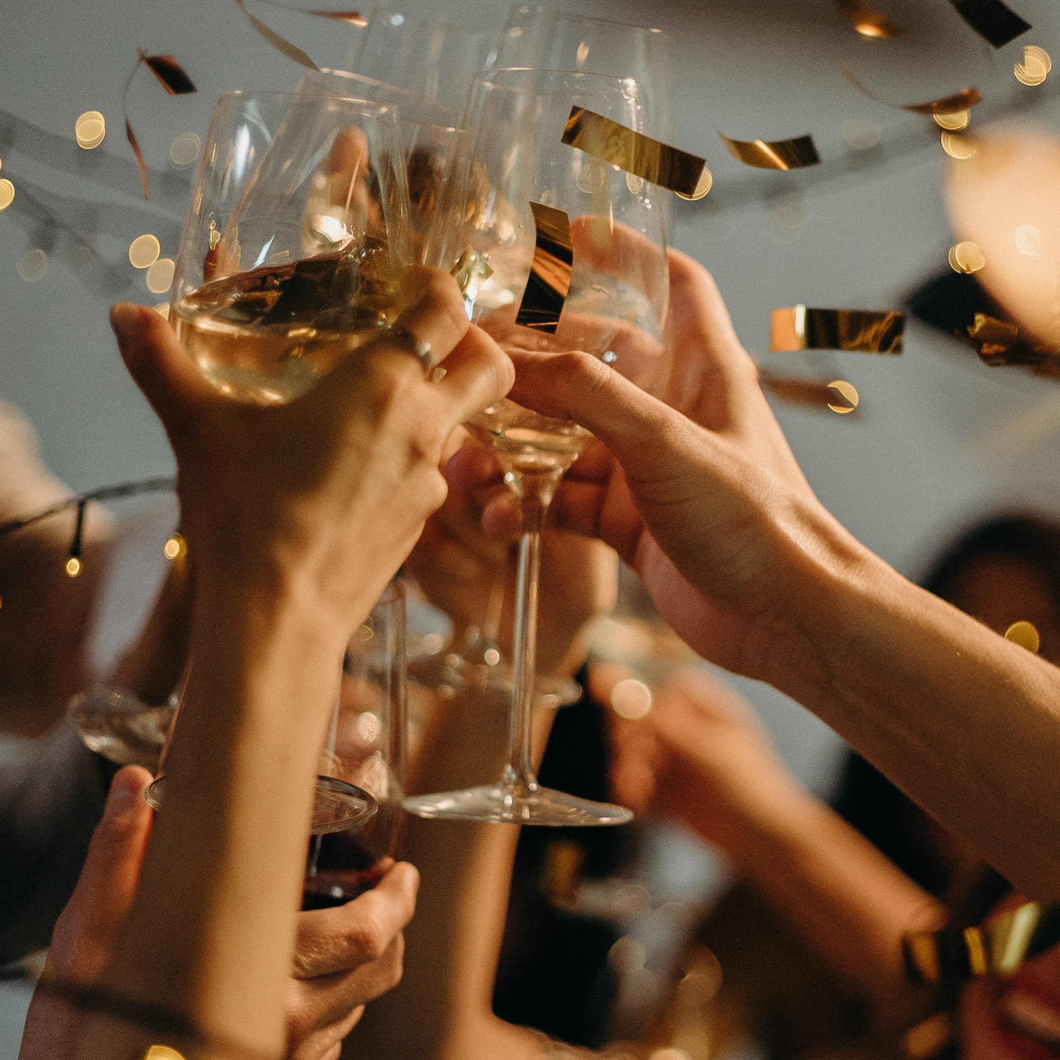 image of wine glasses raised at a party