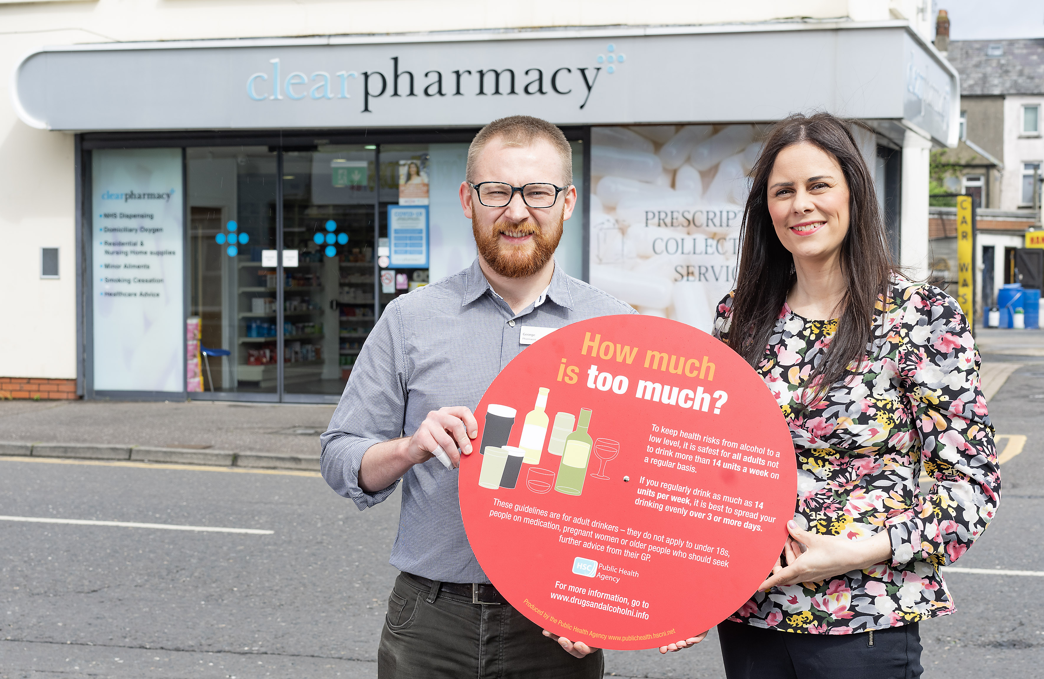 Photograph of Stephanie Hanlon Joint Regional Lead for Drugs and Alcohol, PHA and Pharmacist George Wright, holding the Focus on Alcohol photo prop, outside Clear Pharmacy. 