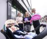 Alt text: Pic shows baby Sullivan asleep in his pram with his mum Gemma behind him, with Pharmacist Edel McMahon and the PHA’s Dr Hannah Dearie in front of Randalstown Pharmacy. They are holding a pink sign saying “I support breastfeeding mums” and a purple sign saying “Breastfeeding Welcome Here”.