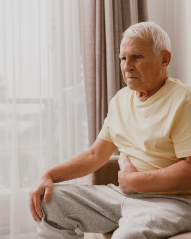 Photograph of a man holding his lower stomach, with a painful facial expression
