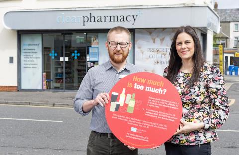 Photograph of Stephanie Hanlon Joint Regional Lead for Drugs and Alcohol, PHA and Pharmacist George Wright, holding the Focus on Alcohol photo prop, outside Clear Pharmacy.
