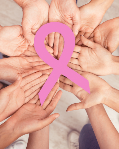 Photograph of women's hands holding breast cancer awareness ribbon in support, during Breast Cancer Awareness Month.