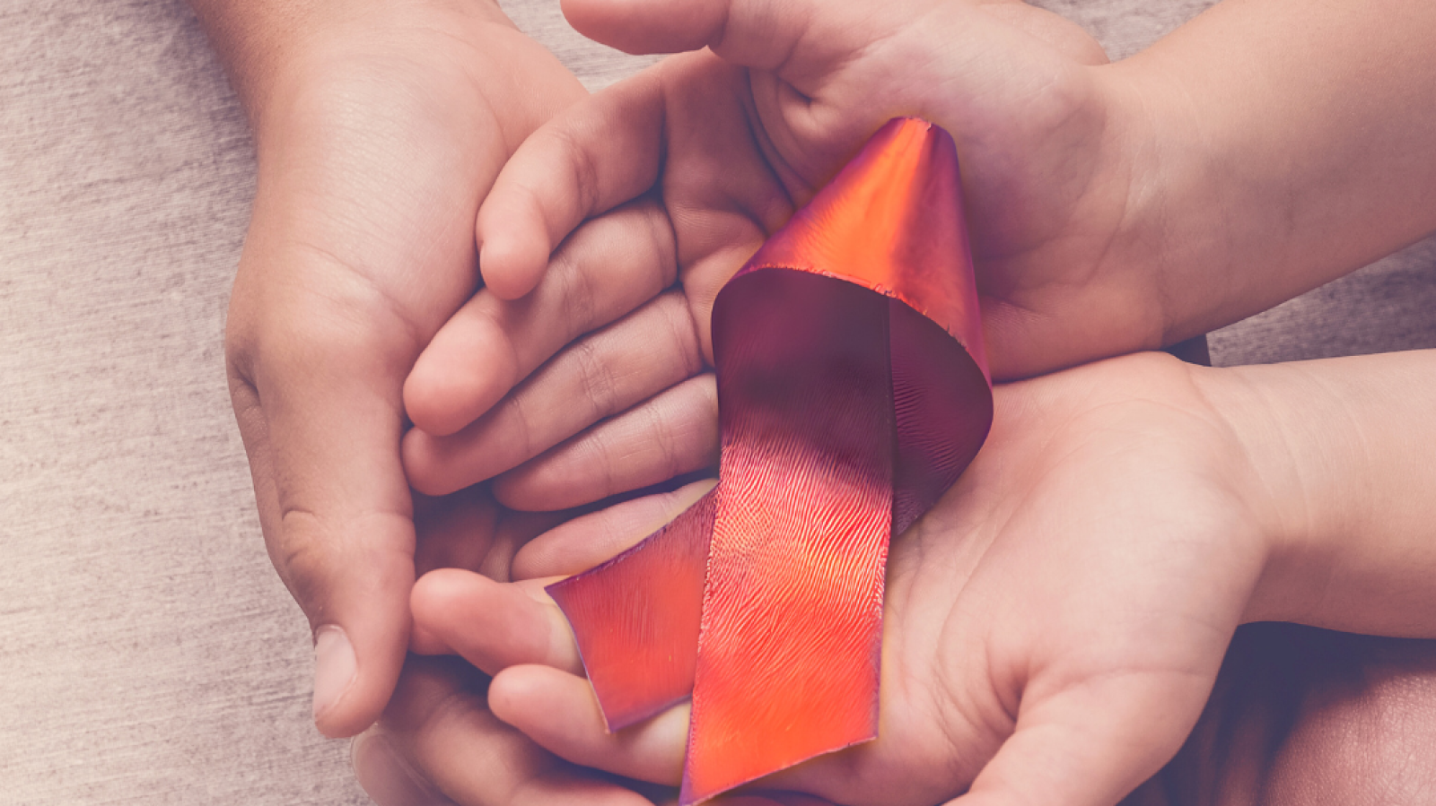 Two sets of hands holding an orange ribbon with text that reads: "Self-harm awareness day"