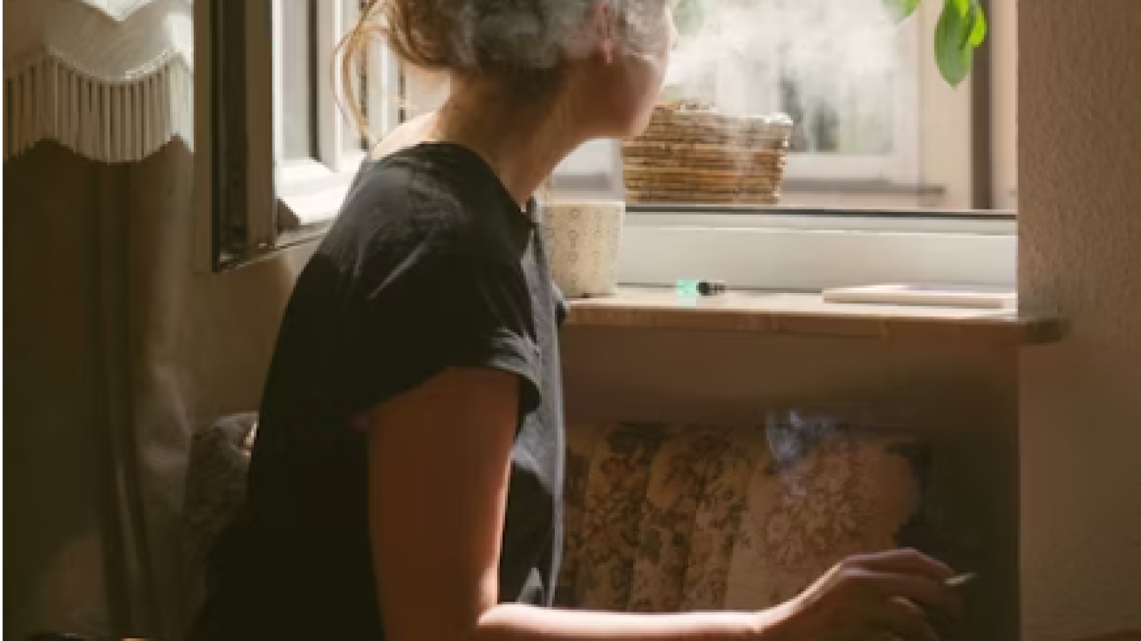 woman smoking in front of open window