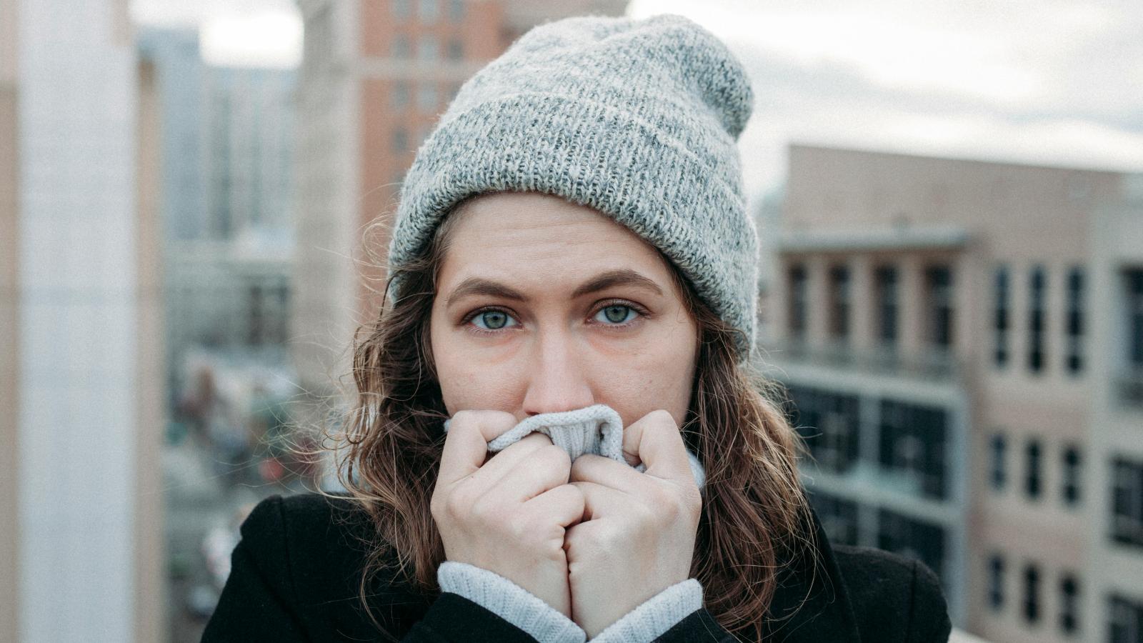 woman in a hat trying to warm up her hands