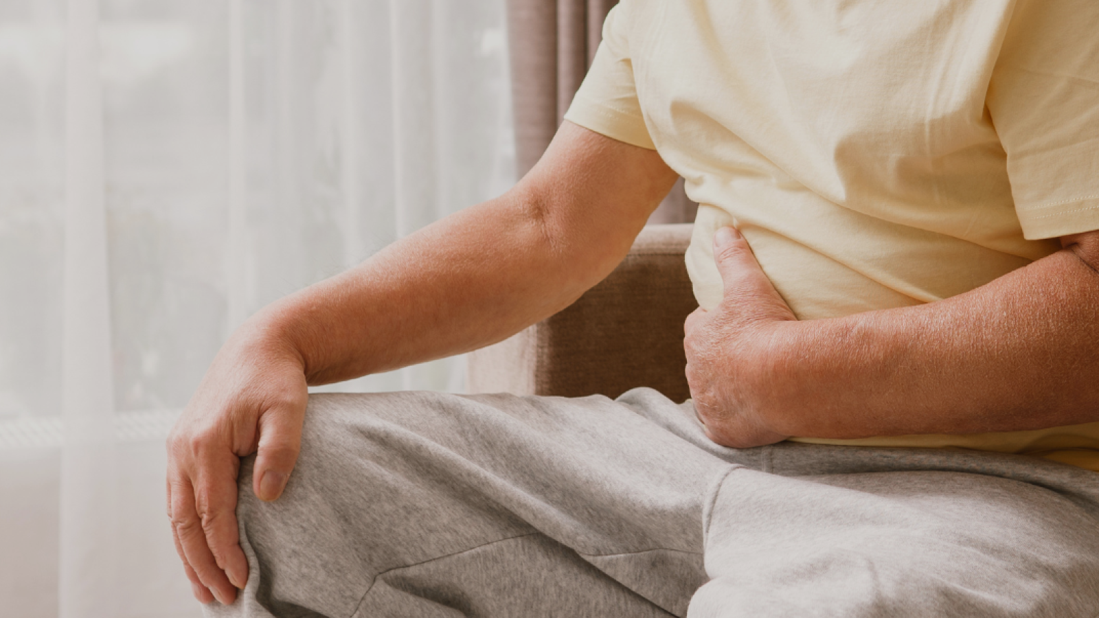 Photograph of a man holding his lower stomach, with a painful facial expression