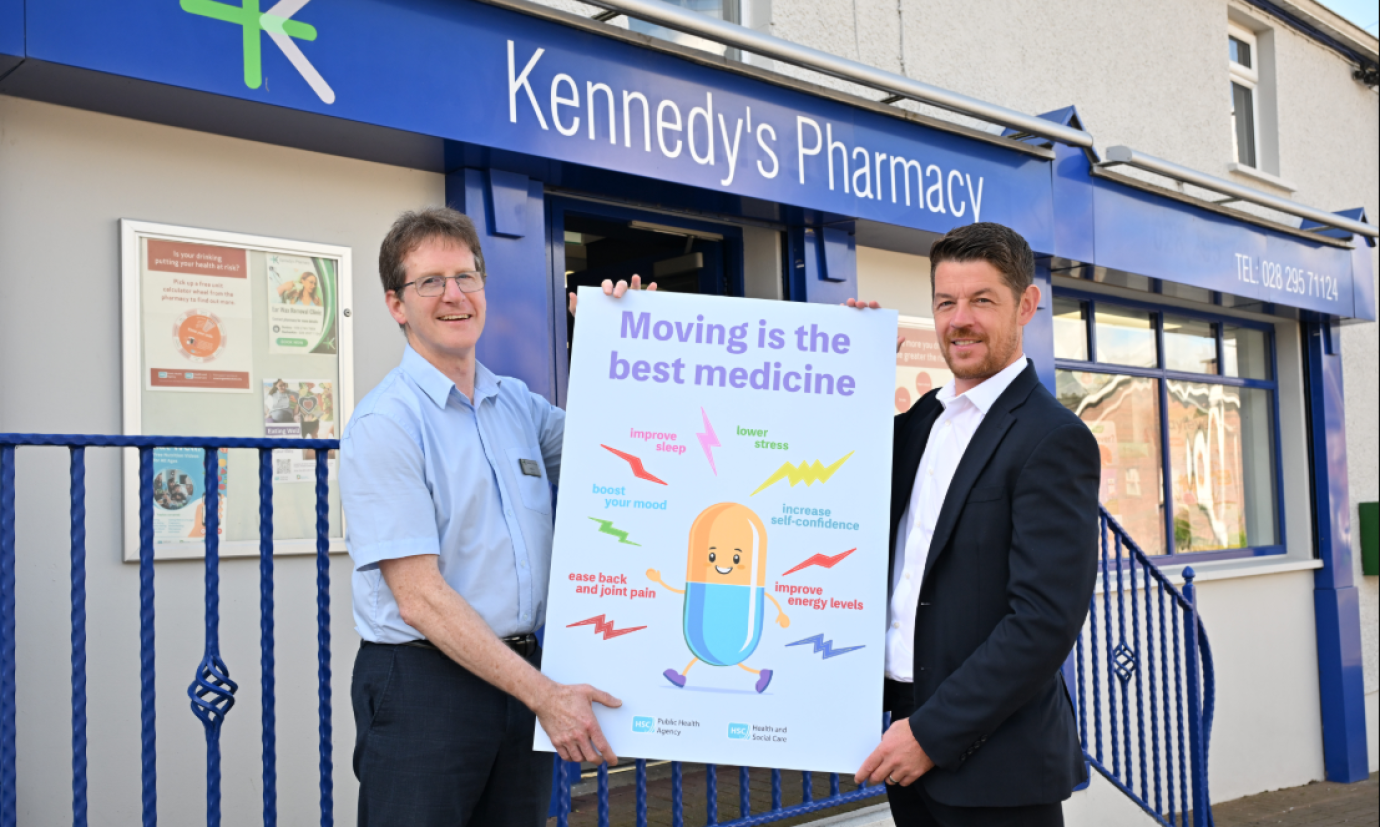 living well move more campaign launch, two men with a poster in front of the pharmacy